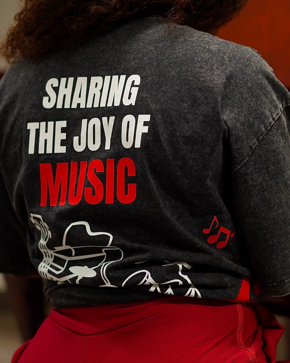An FMA tee reading “Sharing the joy of music”, worn at the piano